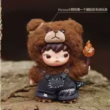 Small figurine of a bear-like character with a person-like face, wearing a hat and coat, on a textured surface.