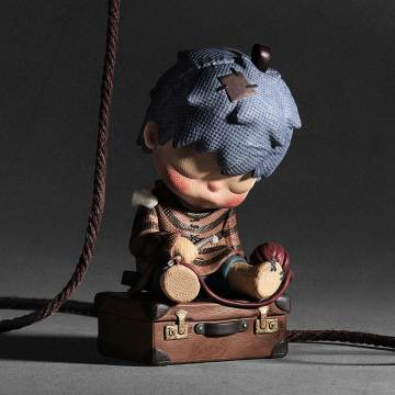 Vintage-style toy figure with a blue hat and brown outfit on a dark background