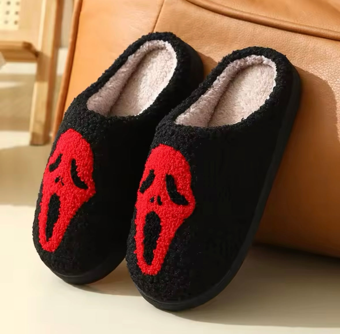 Pair f Black boucle slippers with a red skull face design.