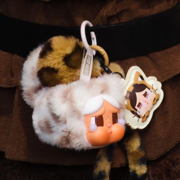 Plush keychain with cartoon character and fluffy ear design on a brown background