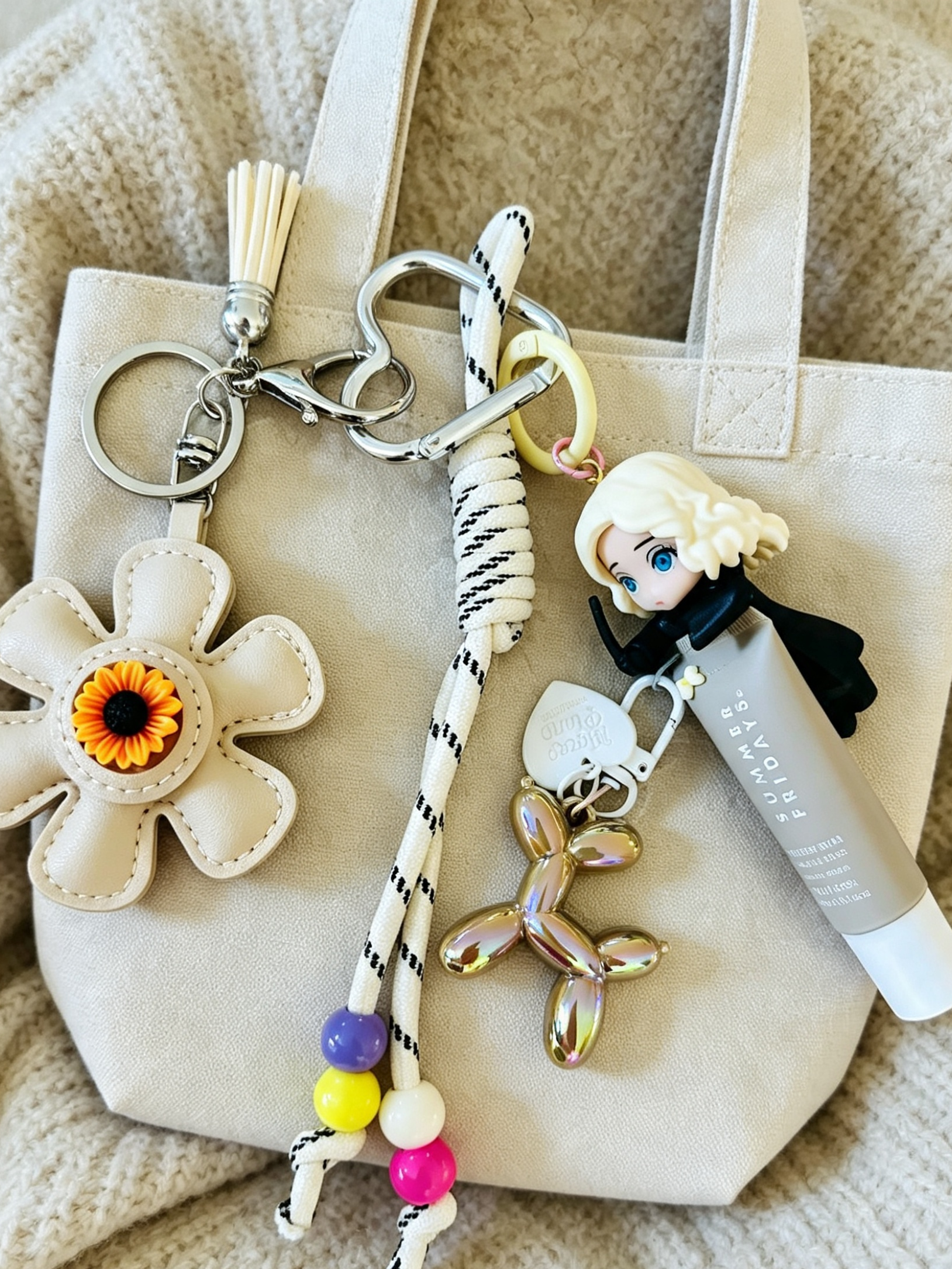 Customised Draco & Daisy bag charm displayed on a beige tote bag with sunflower charm, colourful beads and Summer Fridays Lip Butter