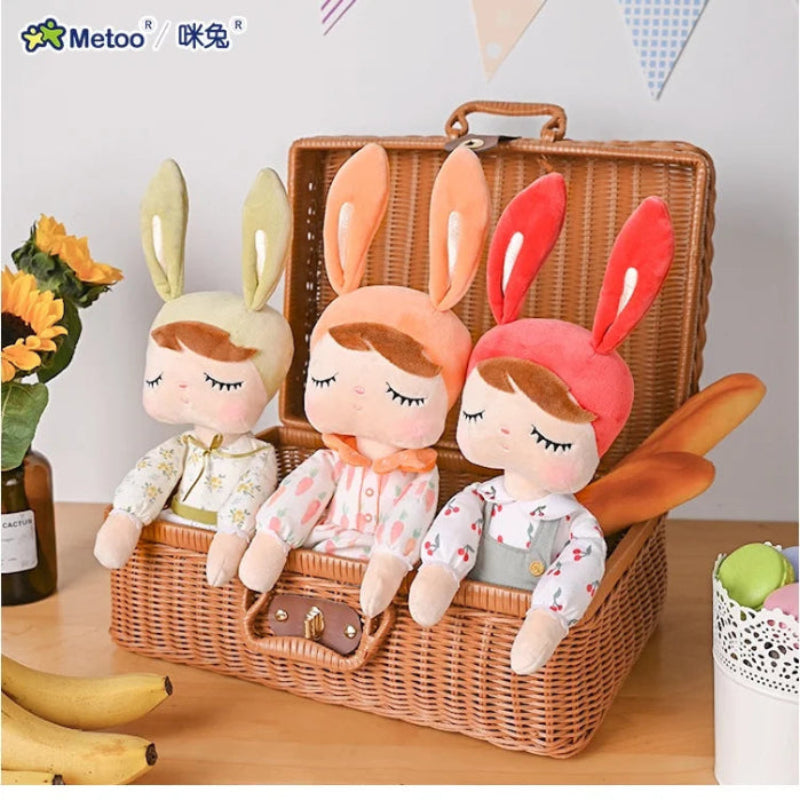 Three plush toys with bunny ears in a wicker basket on a wooden table.