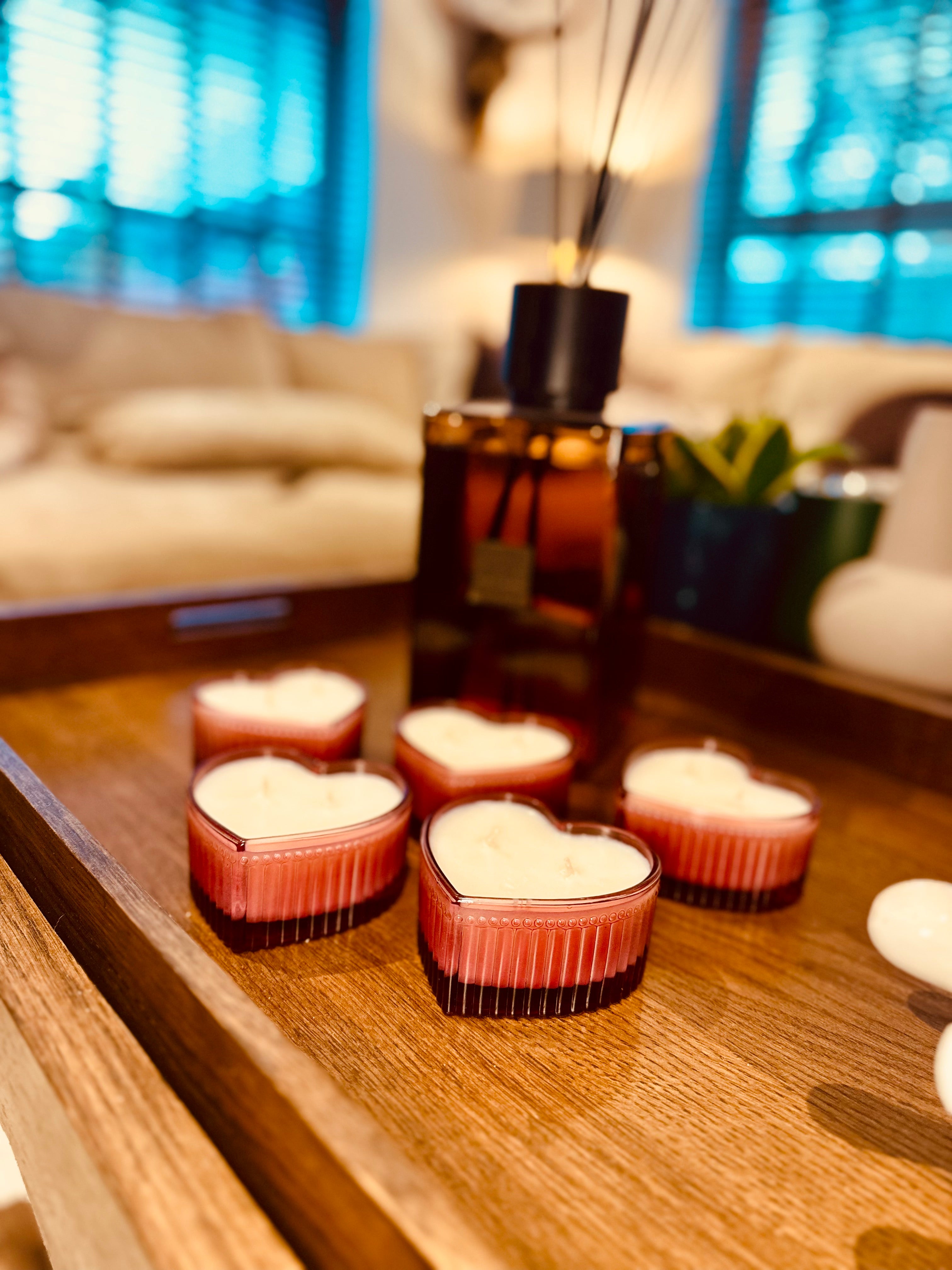 Heart-shaped candles on a wooden table with a blurred living room background