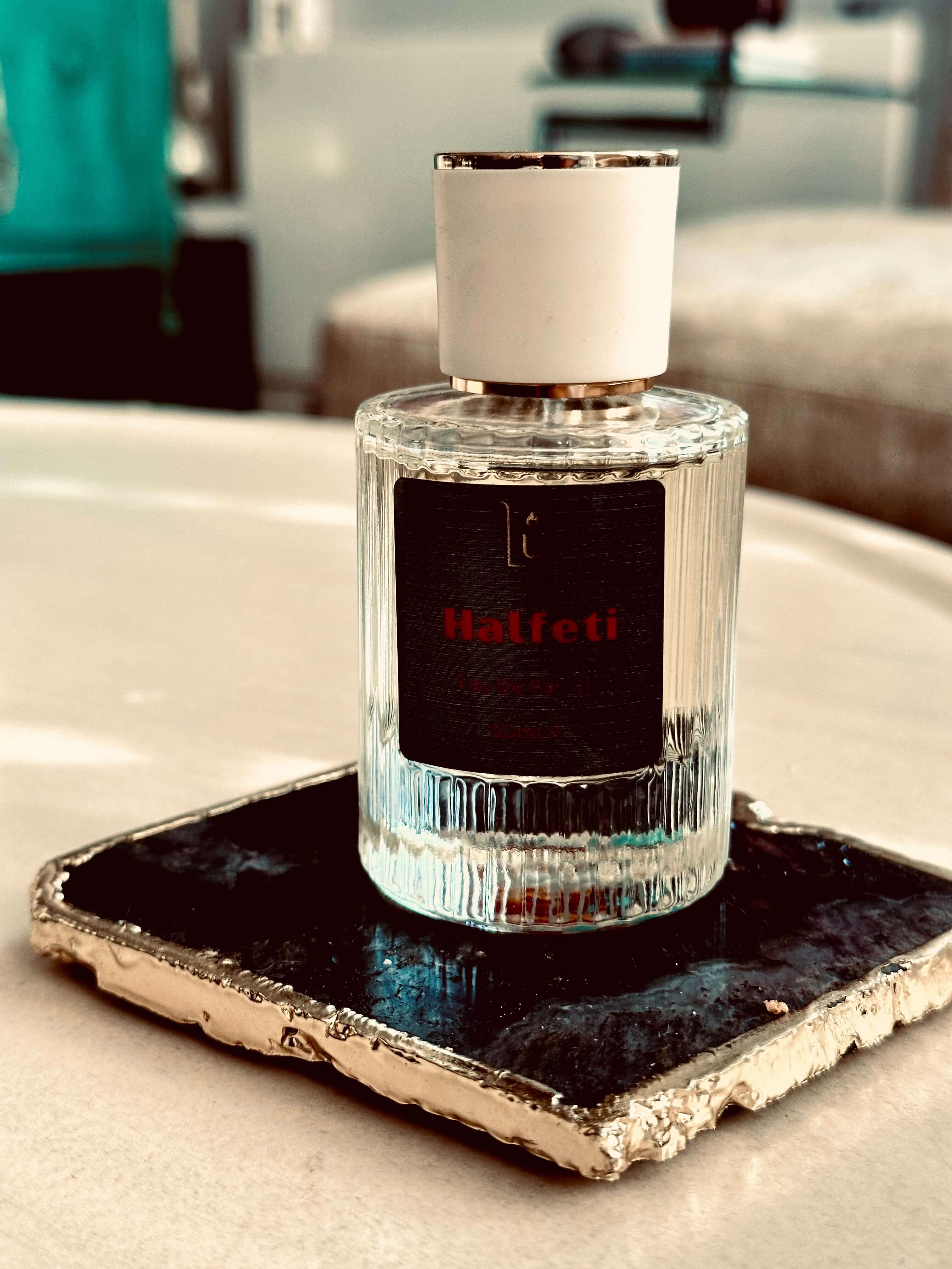 A glass bottle of perfume labeled 'Halfeti' on a dark试纸 surface with a white cap, representing the product mentioned in the description.