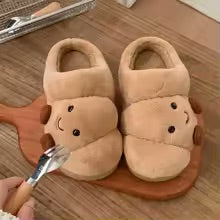 Pair of plush slippers with a croissant shape design on a wooden floor.