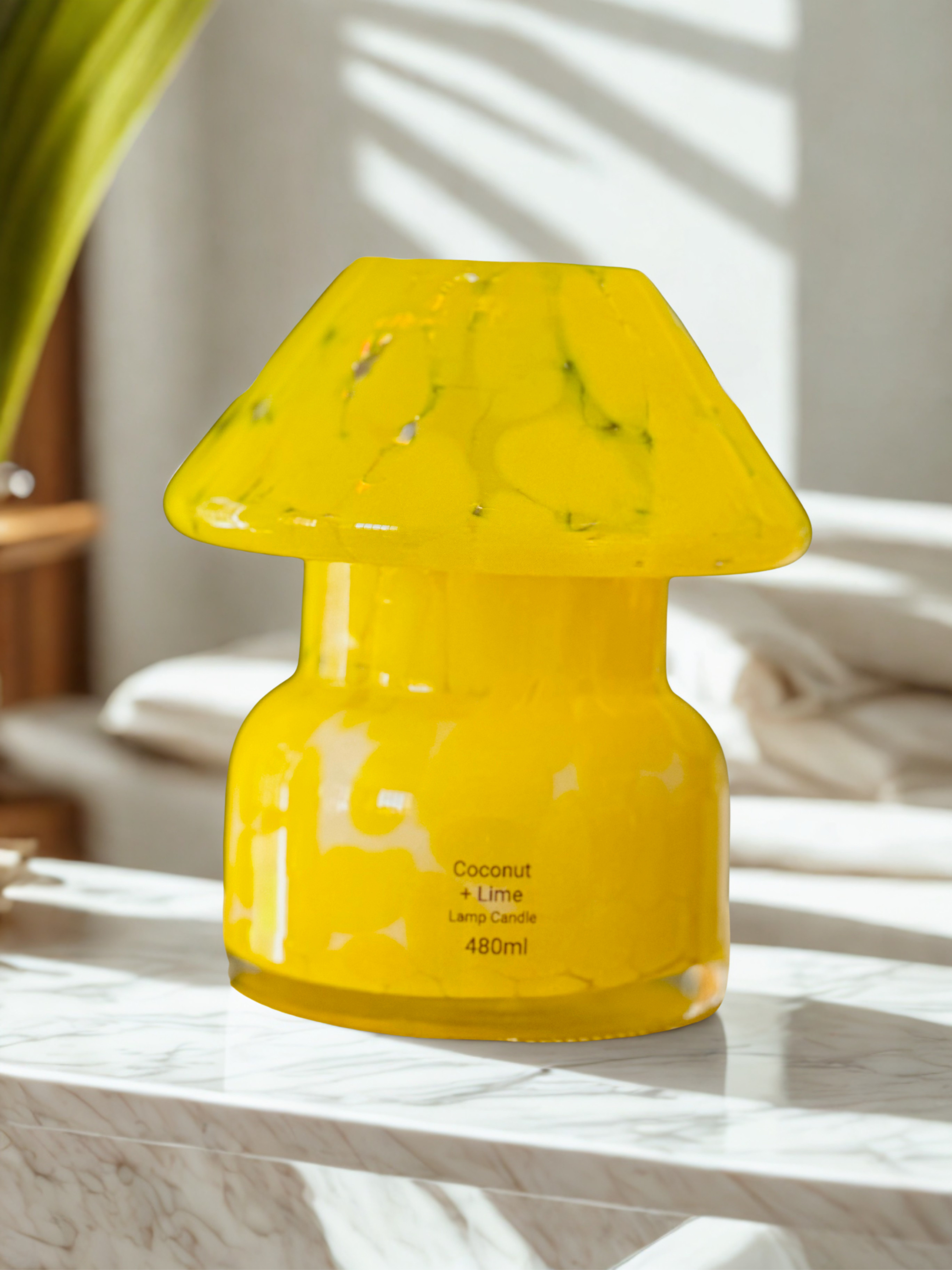 Yellow coconut lime candle on a marble surface with a blurred background