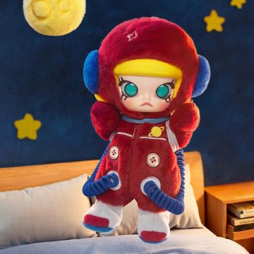 Plush toy in a red outfit with blue accents on a bed with a starry night background