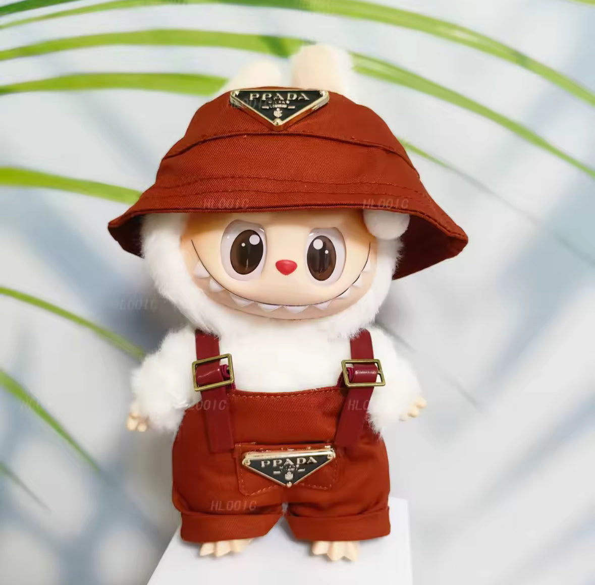 Labubu figure wearing a Prada hat and dungarees on a white background