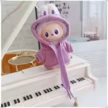 Plush toy character in a purple hoodie with bunny ears on a small white piano.