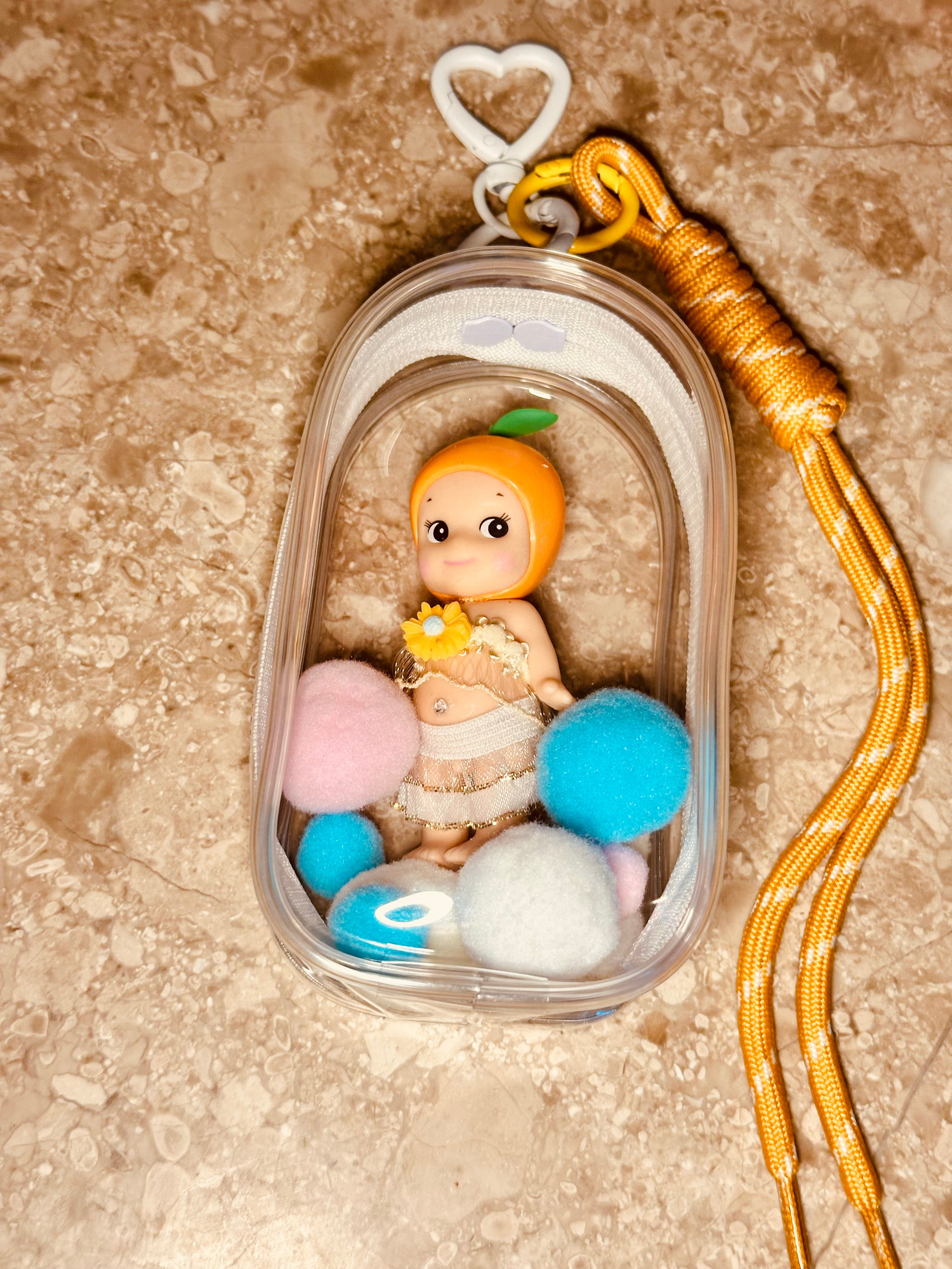 Small figurine inside a clear container with colorful balls on a textured surface