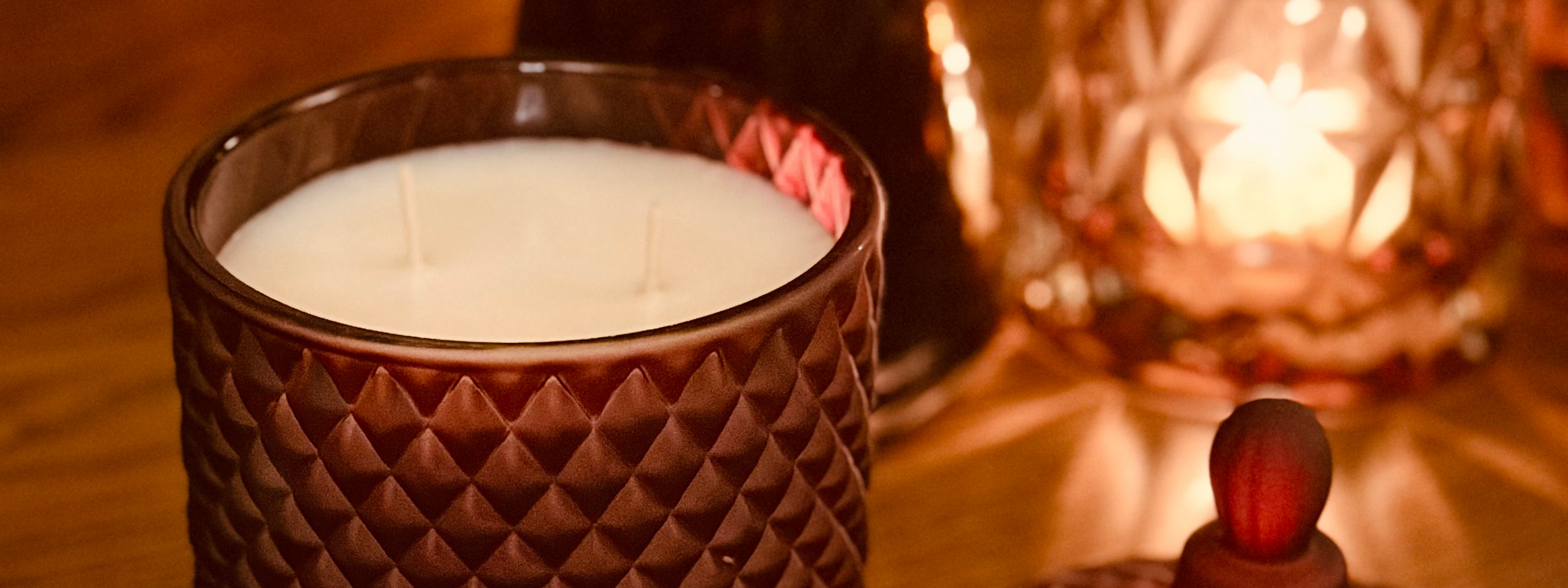 Candle in a textured glass holder with a blurred background