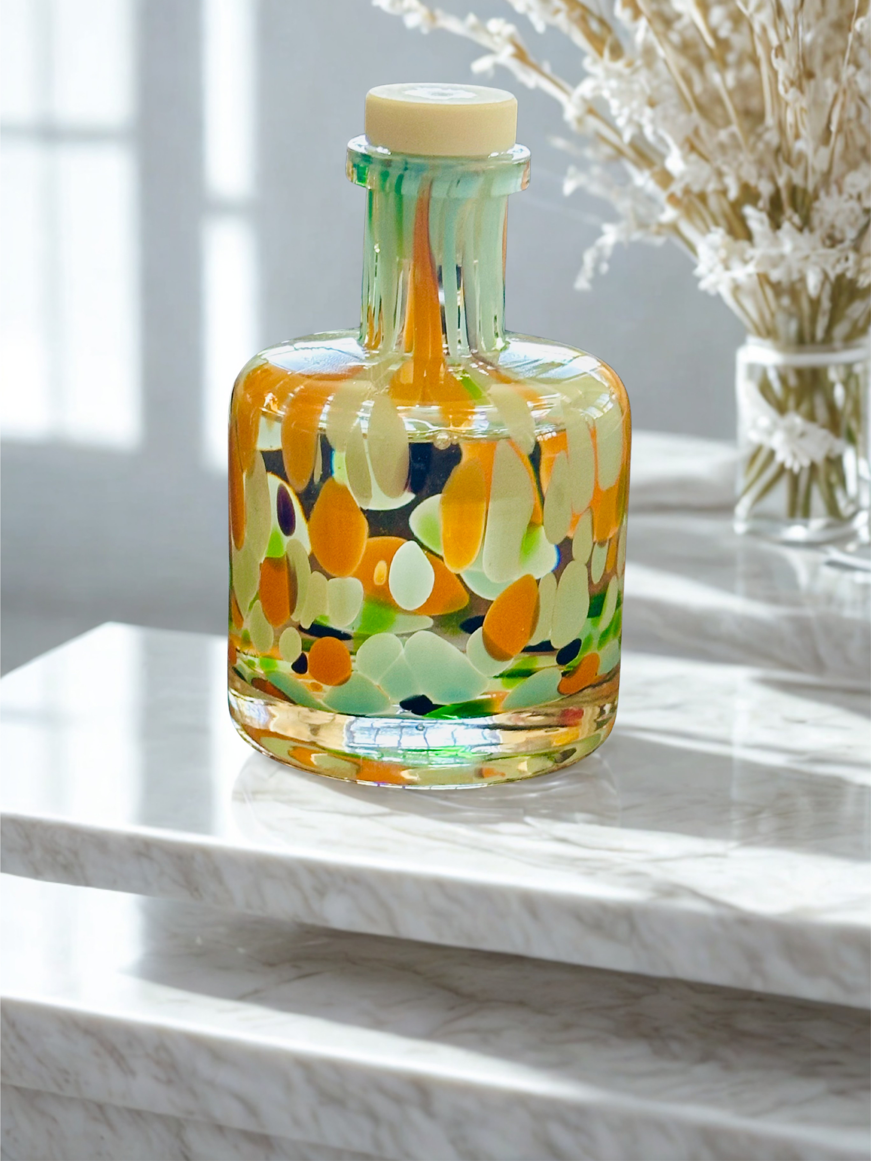 Decorative glass bottle with colorful design on a marble surface