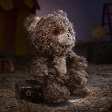 Brown teddy bear sitting on a wooden floor.