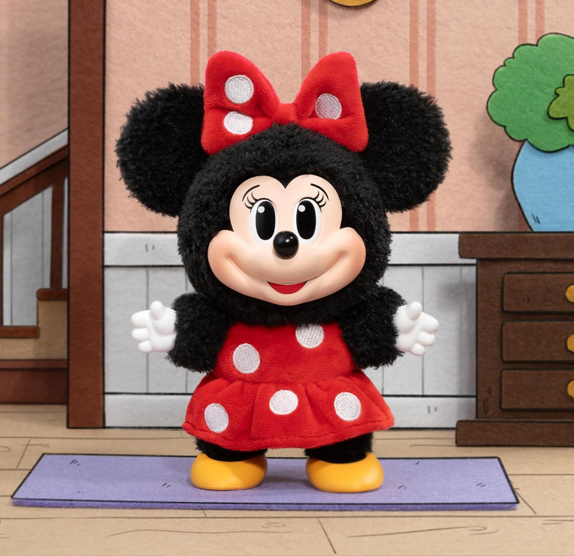 Plush toy of a character in a red dress with white polka dots and a red bow on a rug.