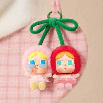 Two small figurines with colorful hair and outfits on a pink checkered fabric background.
