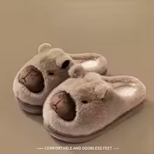 Pair of fluffy slippers with bear design on a beige background