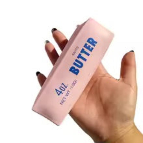 A hand holding a pink rectangular container of 4oz cold-pressed butter soap with blue text reading '4oz BUTTER'.