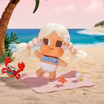 Toy figure of a girl in a bikini on a beach with a palm tree and ocean in the background