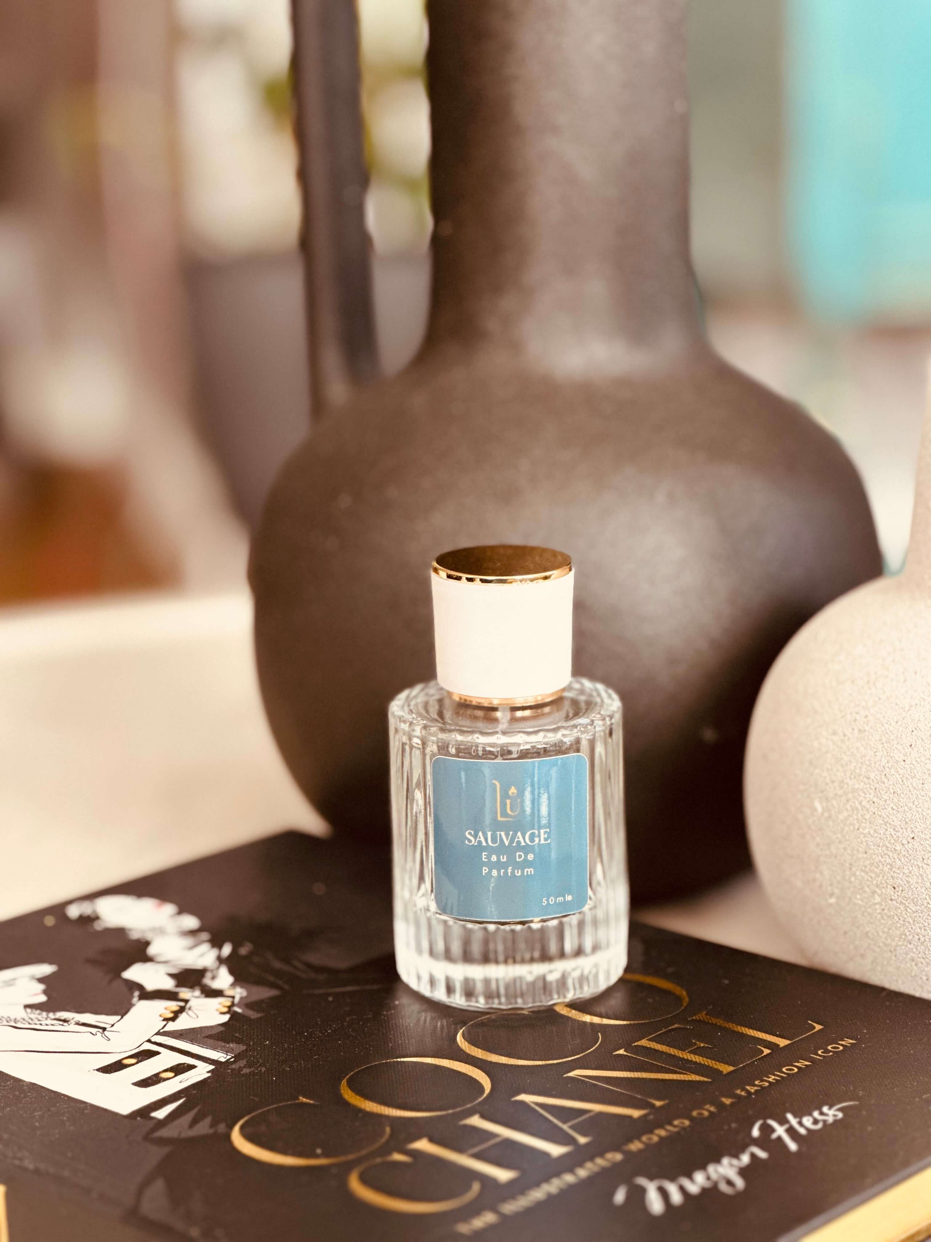 Fresh Bergamot & Ambroxan Eau de Parfum by LU Fragrances — 50ml glass bottle with blue label and white cap, styled on a Coco Chanel coffee table book with dark ceramic vases