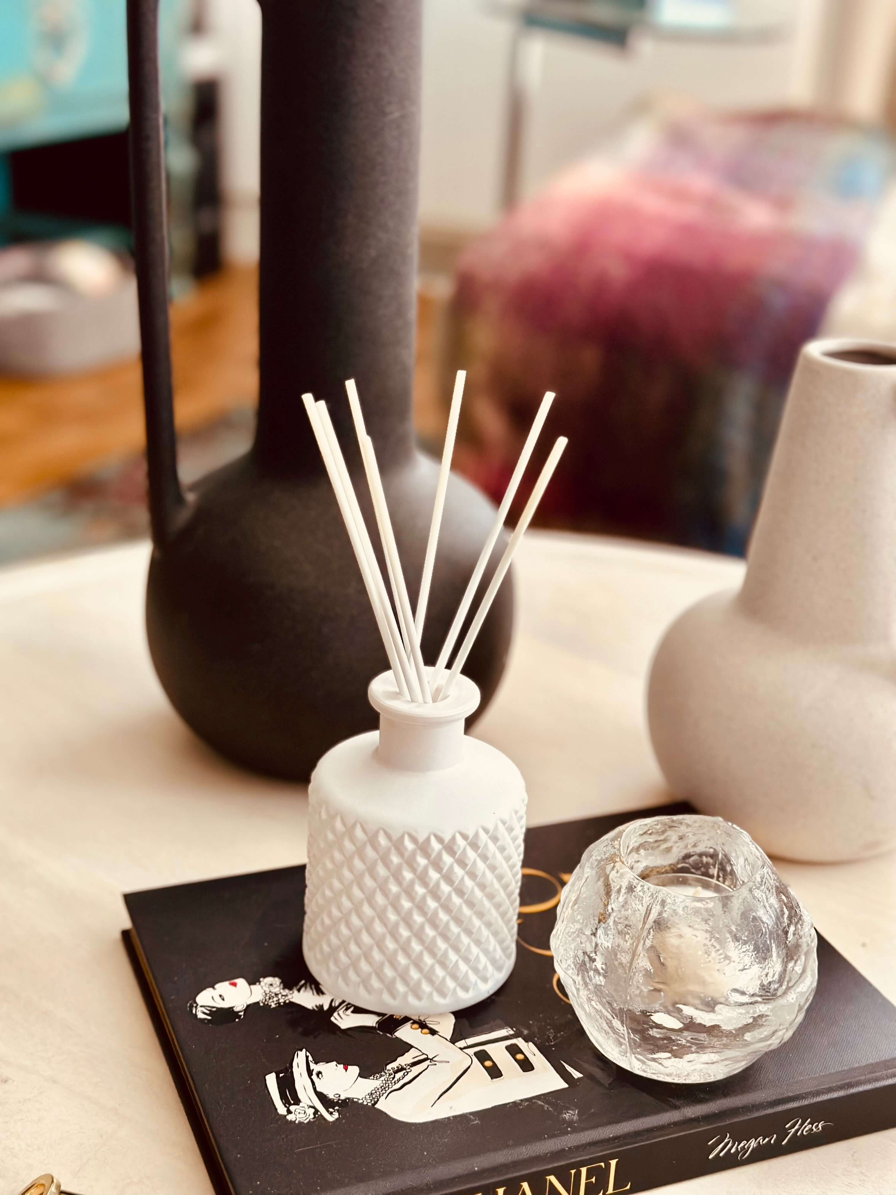 white reed diffuser with reeds on a black book