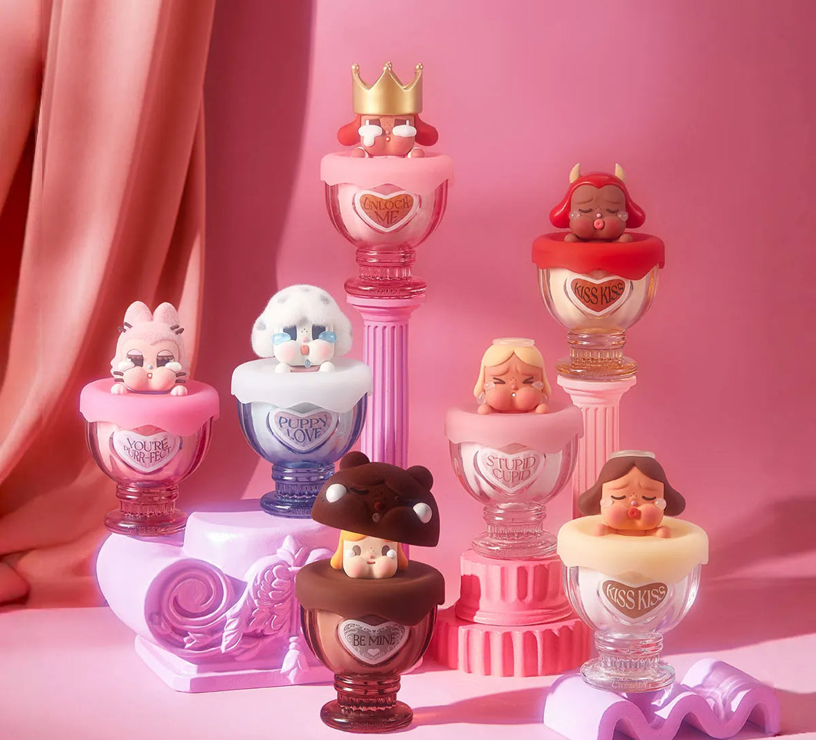 Collection of decorative figurines on a pink stand with a pink curtain background