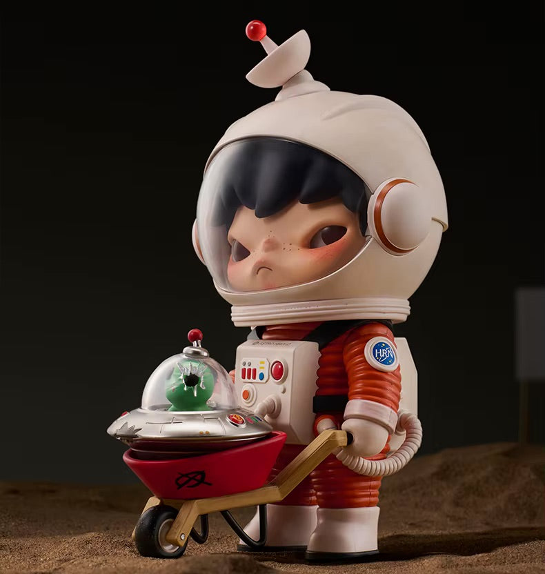 Toy figure of a child in an astronaut suit holding a small greenhouse on a dark background
