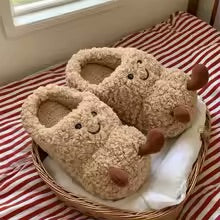 Pair of plush animal-shaped slippers on a red and white striped blanket.
