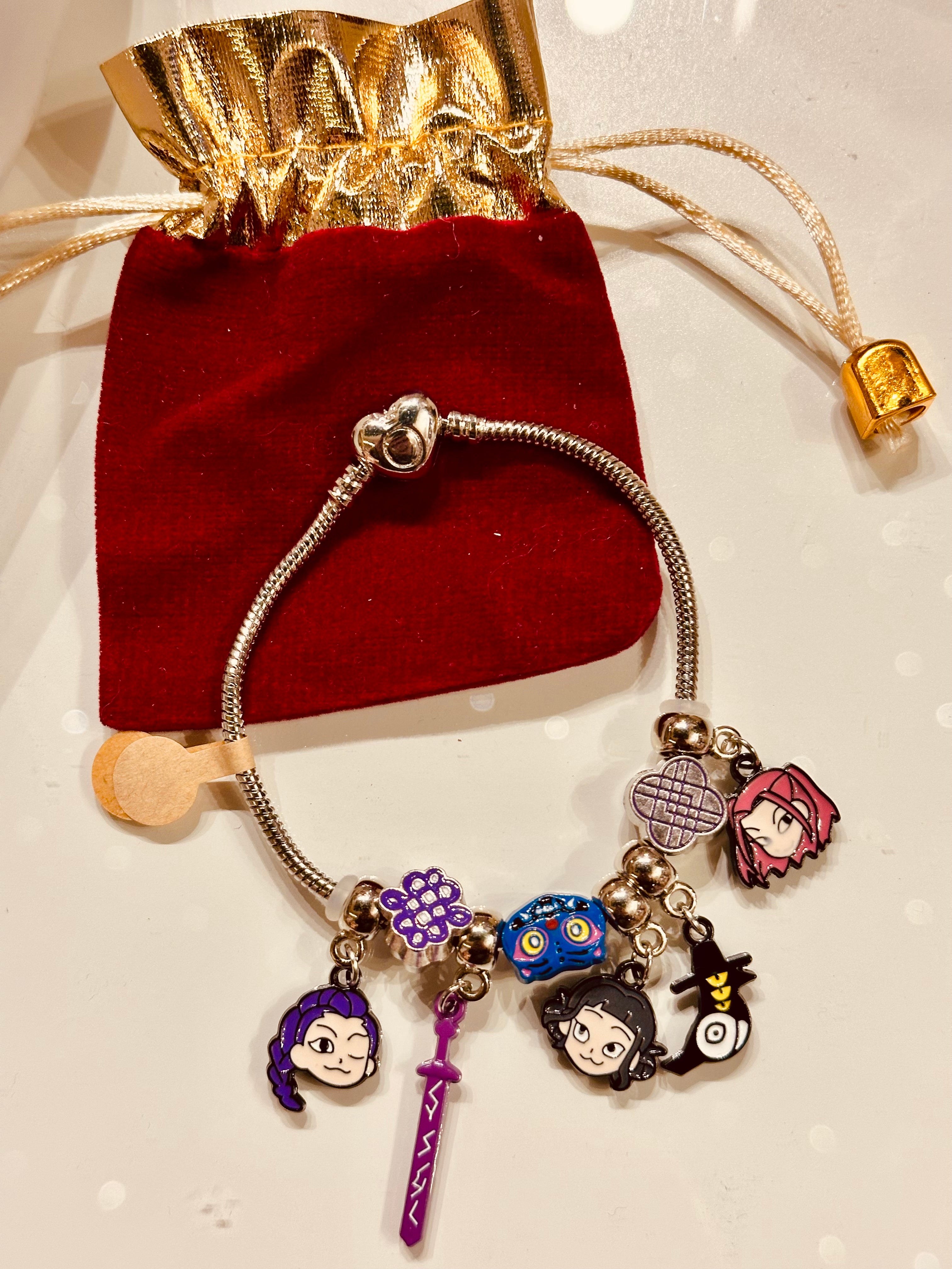 Charm bracelet with various charms on a red velvet bag