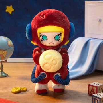 Plush toy figure in a red space suit with blue accents on a wooden floor.