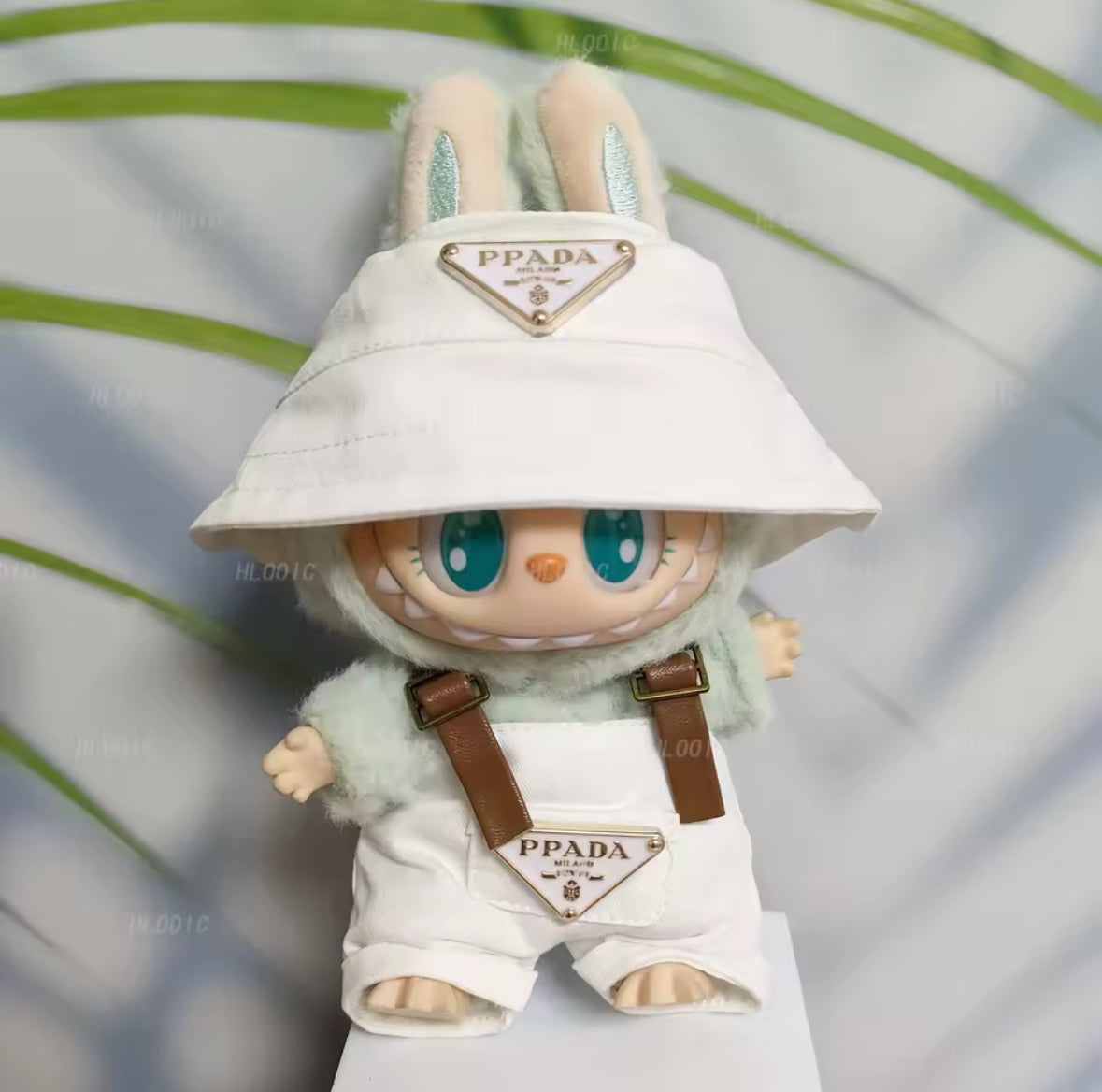 Toy figure with a bucket hat and dungarees , featuring Prada branding, against a blurred natural background.