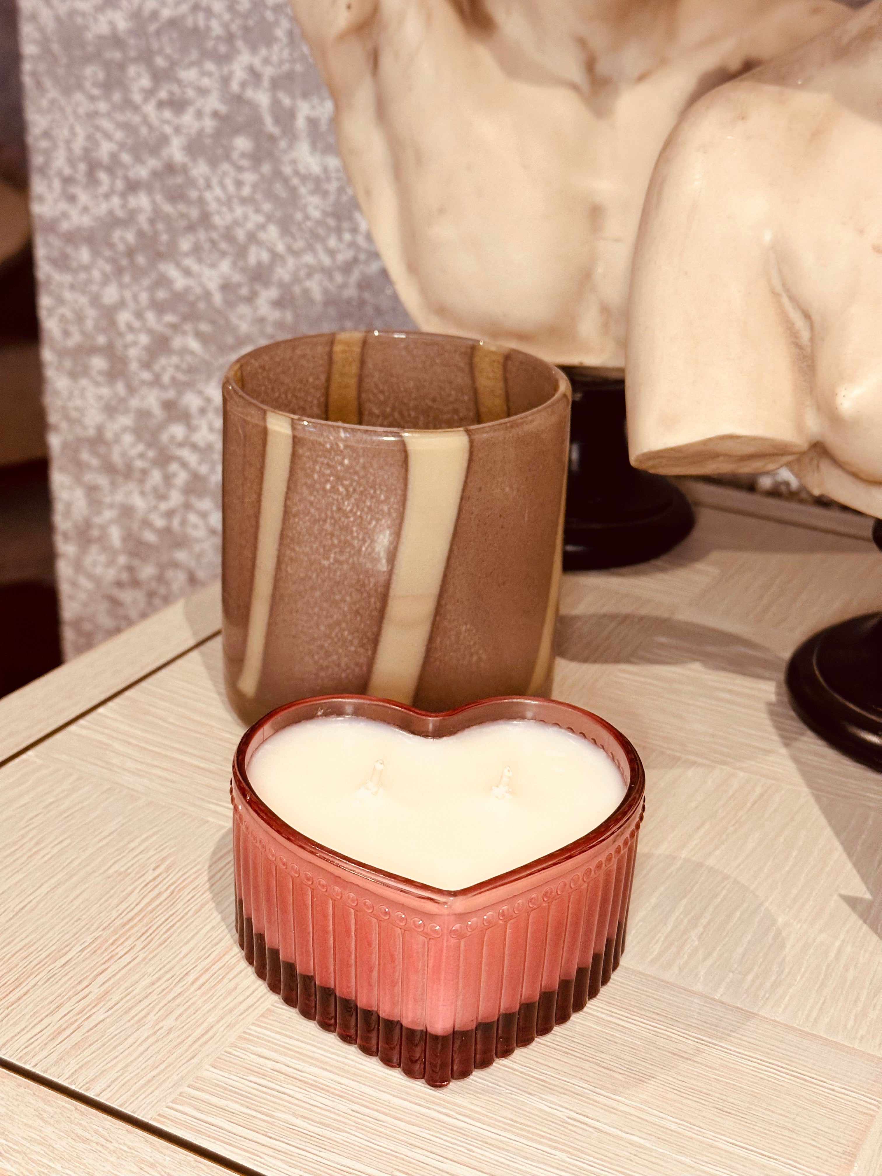 Heart-shaped ceramic container with a striped cup on a textured surface
